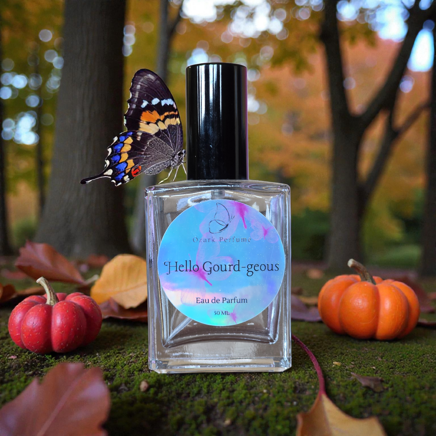 Perfume bottle labeled 'Hello Gourd-geous' with pumpkins and a butterfly in an autumn setting