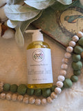 Bottle of Tidylifecan Soap & Co. body oil on a decorative background with green and white beads.