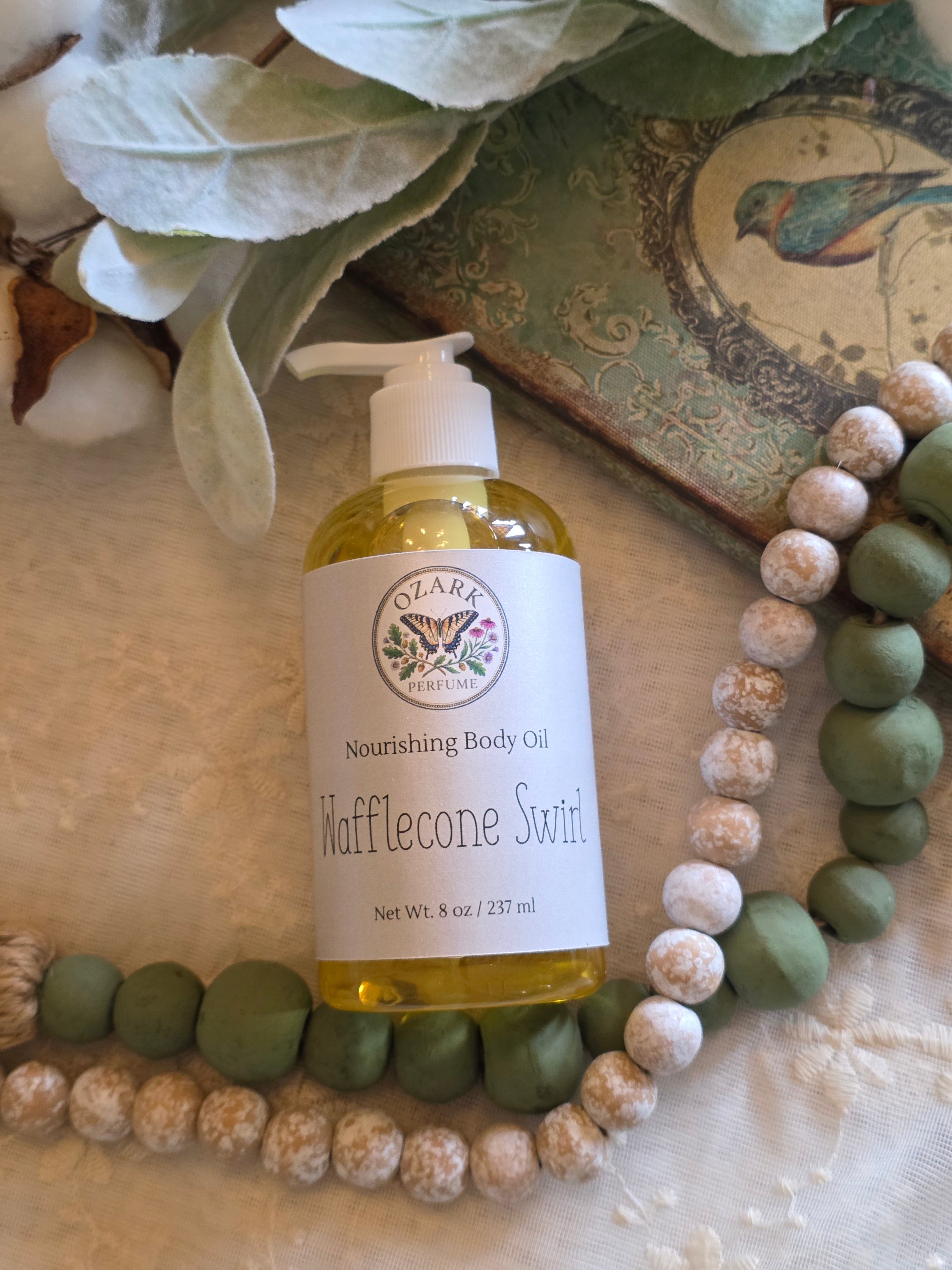 Bottle of Tidylifecan Soap & Co. body oil on a decorative background with green and white beads.