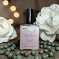 Perfume bottle labeled 'Whipped Honey Butter' with white flowers and green beads in the background