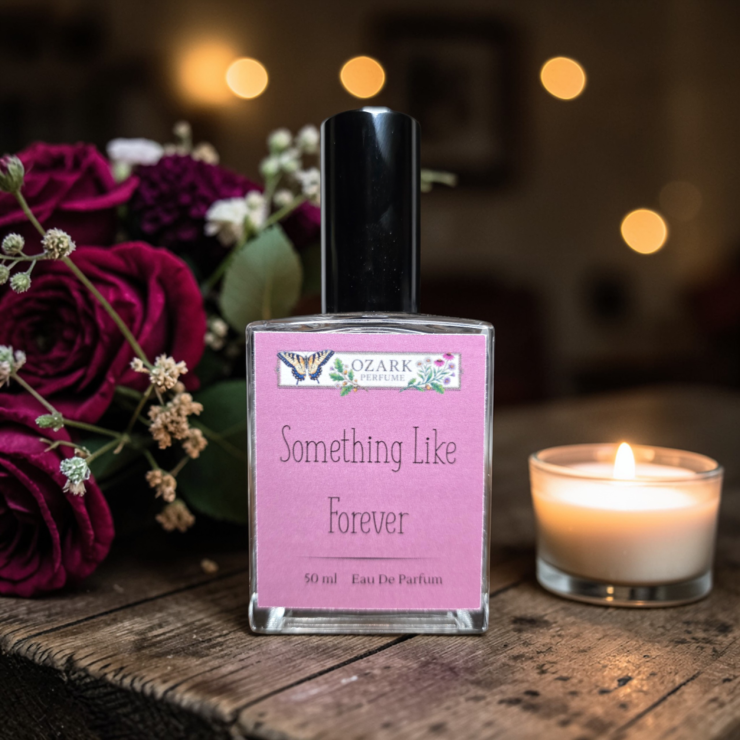 Perfume bottle labeled 'Something Like Forever' with flowers and a candle on a wooden surface.