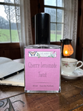 Perfume bottle labeled 'Cherry Lemonade Twist' by Ozark Trail on a wooden table with a window and candle in the background.