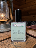 Perfume bottle labeled 'Date Night' by Ozark perfume on a wooden surface with a lantern and book in the background.