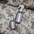 Two 'Welcome Home' spray bottles on a floral fabric background