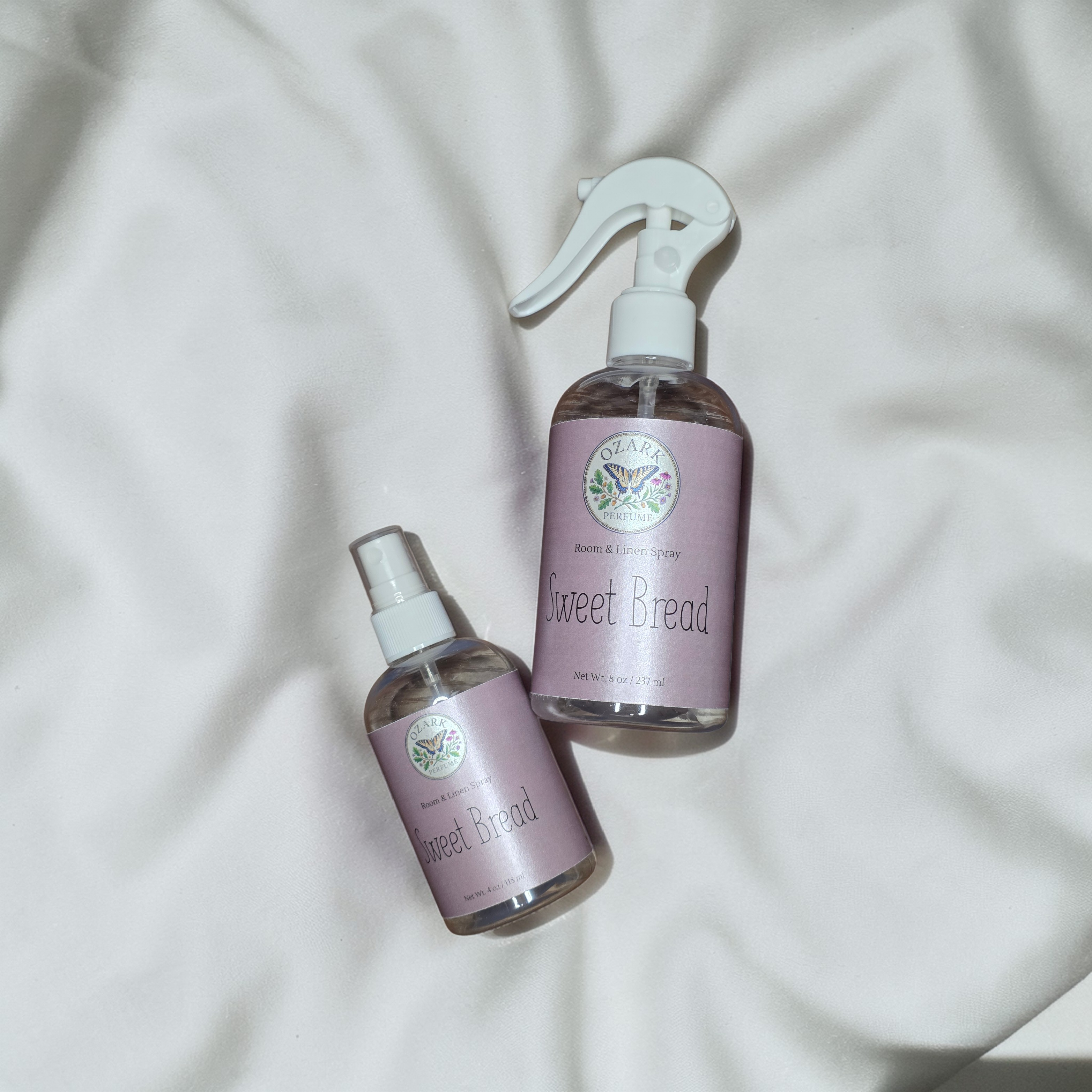 Two bottles of 'Sweet Bread' on a light fabric background