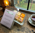Packaged pumpkin pecan gingerbread wax melts on a wooden surface with a cup of tea and decorative elements.