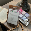 Packaged wax melts labeled 'Purple Cotton Candy' by Ozark Culture on a wooden surface with a book and beads.
