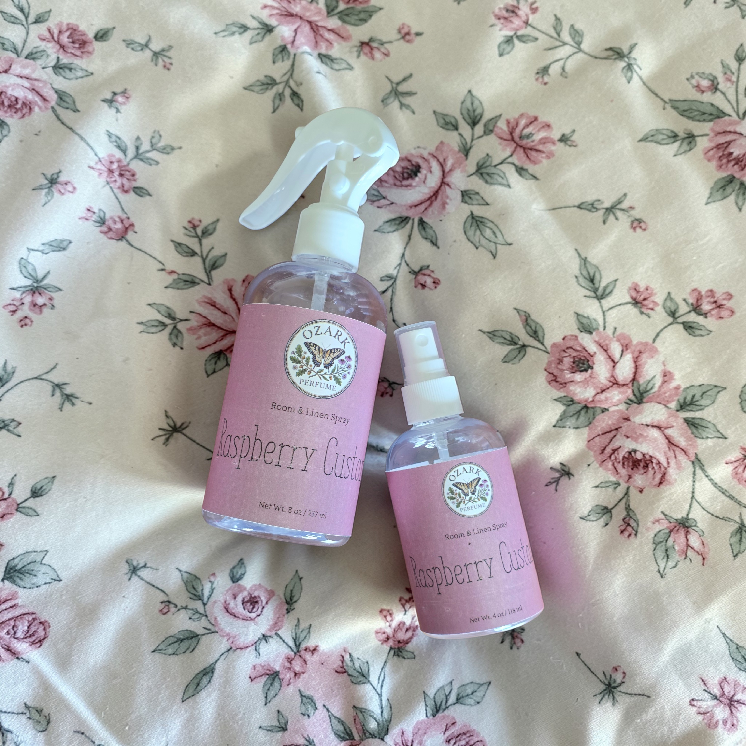 Two Raspberry Gusto spray bottles on a floral fabric background