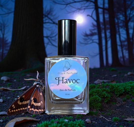Perfume bottle labeled 'Havoc' with a moth on a forest floor background