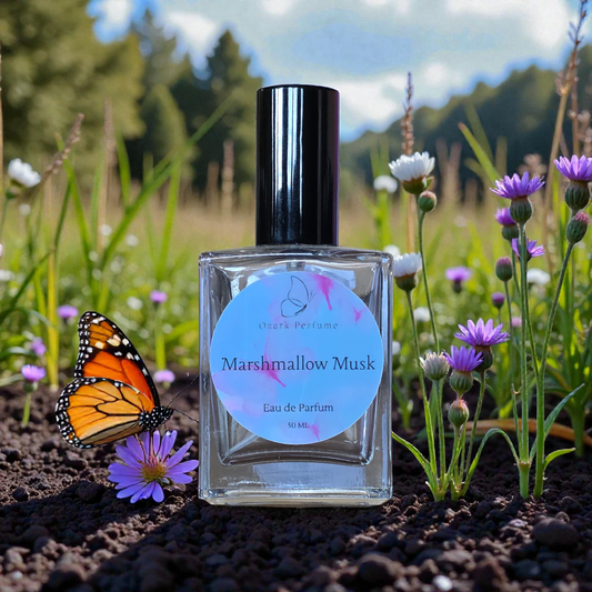 Perfume bottle labeled 'Marshmallow Musk' with a butterfly on a natural background of flowers and grass.