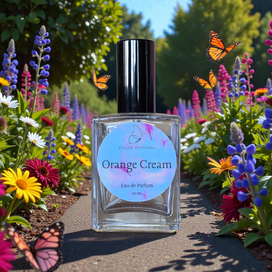 Perfume bottle labeled 'Orange Cream' surrounded by butterflies and colorful flowers