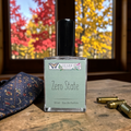 Perfume bottle labeled 'Zero State' by 'Ozark Perfume' on a wooden surface with autumn trees in the background.