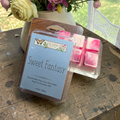 Ozark Perfume Art wax melts called sweet fantasy on a wooden surface with flowers in the background