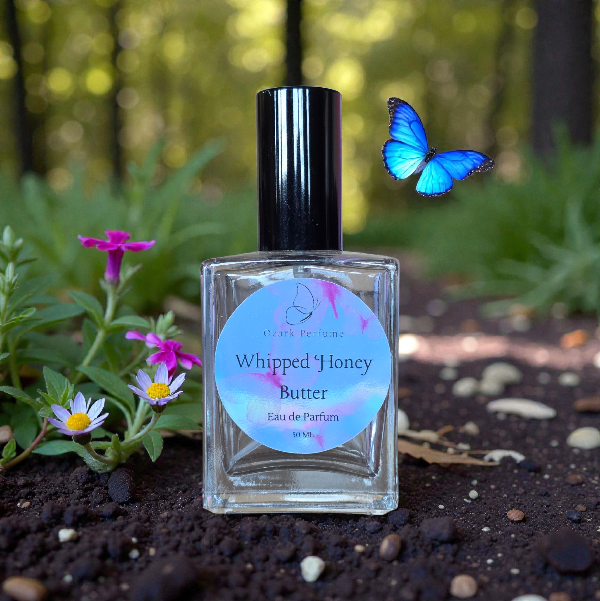 Perfume bottle labeled 'Whipped Honey Butter' with a blue butterfly and flowers in a natural setting