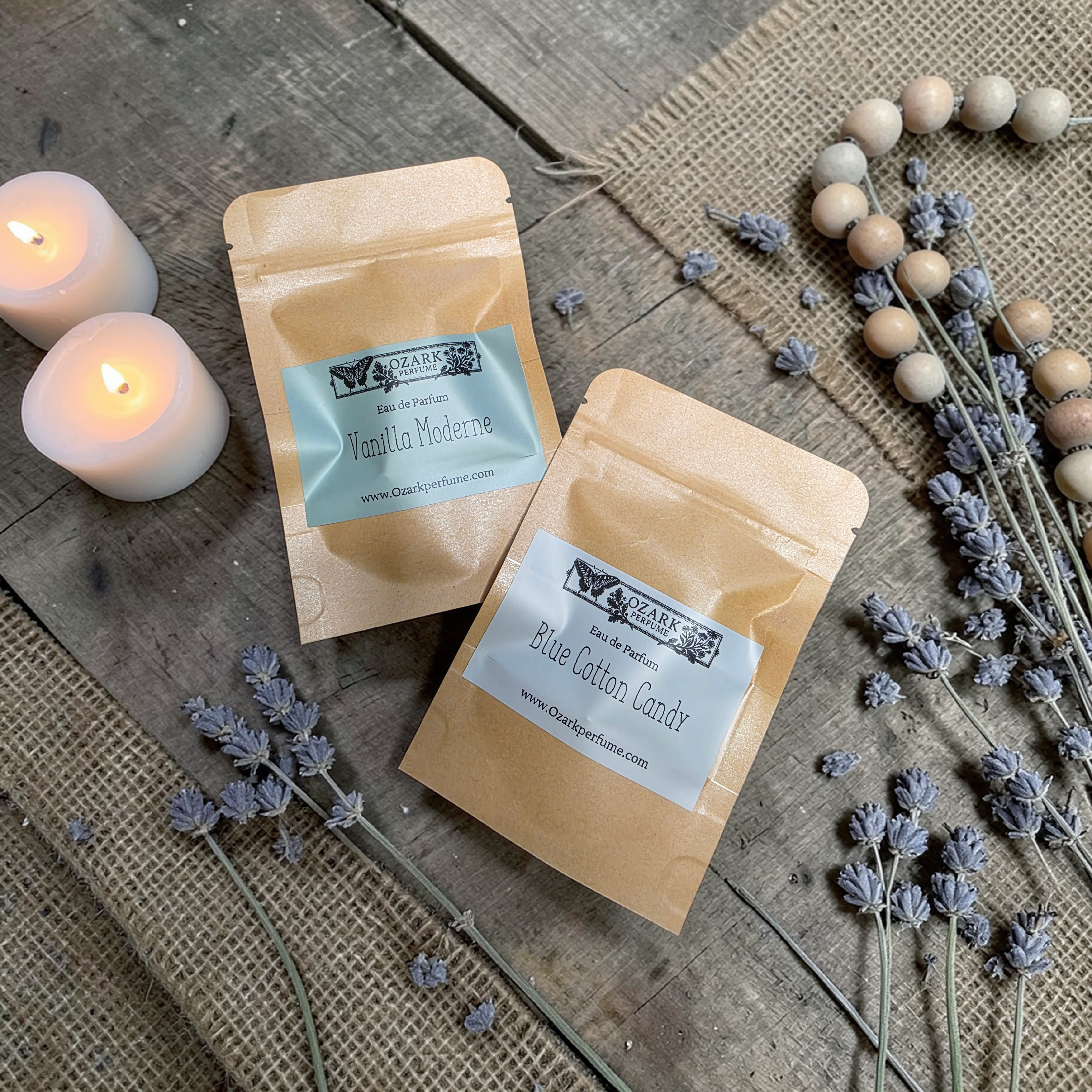 Two packages of eau de parfum with lavender and candles on a wooden surface